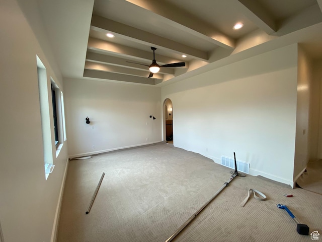 empty room with arched walkways, beam ceiling, visible vents, carpet, and ceiling fan