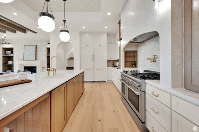 213 W 250 S Unit 15, Mapleton, UT 84664 - kitchen with range with two ovens, a sink, light wood-type flooring, white cabinets, and hanging light fixtures