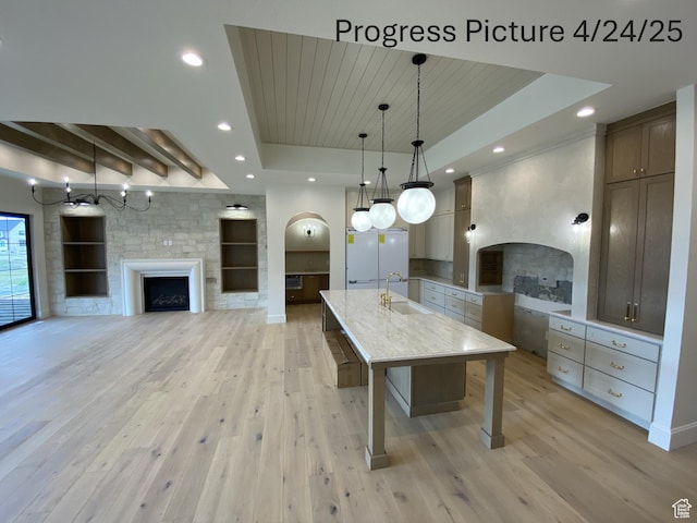kitchen featuring open floor plan, a fireplace, light wood-style floors, and a raised ceiling