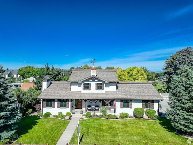 view of front of house with a porch, a front yard, and a chimney
