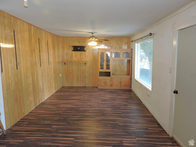 spare room featuring wooden walls, dark hardwood / wood-style flooring, and ceiling fan