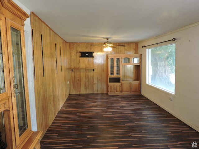 interior space with ceiling fan, wood walls, and dark hardwood / wood-style floors