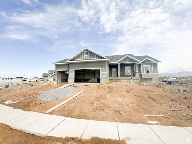 view of front facade with board and batten siding, an attached garage, a shingled roof, and driveway