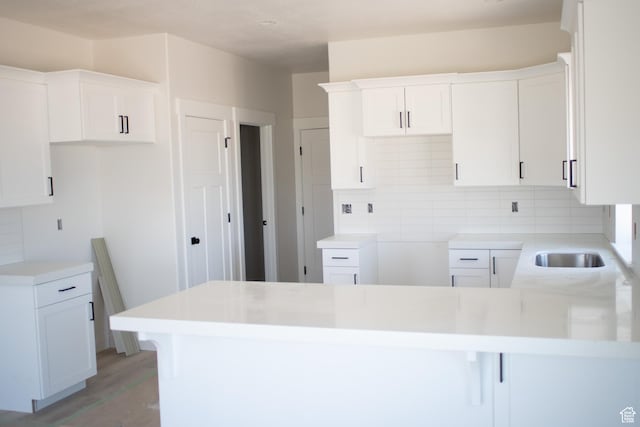 3634 S Macy Ln, West Haven, UT 84401 - kitchen with a peninsula, tasteful backsplash, white cabinetry, light wood-style flooring, and a sink
