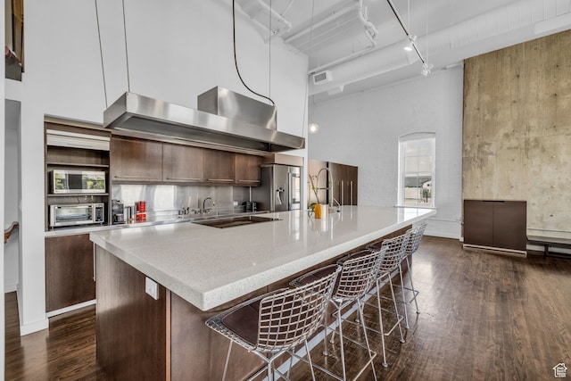 159 W Broadway Unit 301, Salt Lake City, UT 84101 - kitchen featuring a kitchen breakfast bar, stainless steel appliances, dark hardwood / wood-style flooring, rail lighting, and a towering ceiling