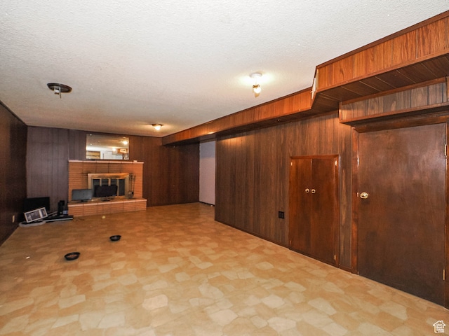 unfurnished living room with a textured ceiling, wood walls, a fireplace, and tile floors