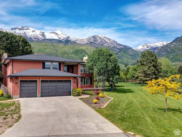 view of front of home featuring a mountain view, a garage, and a front lawn