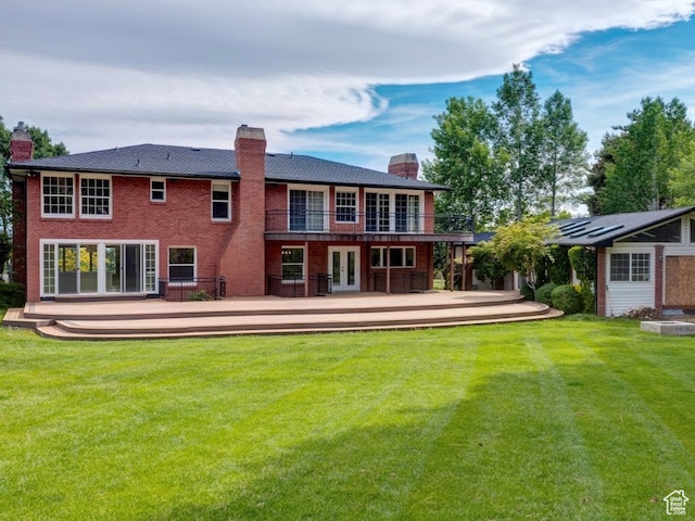 back of property featuring a wooden deck and a lawn