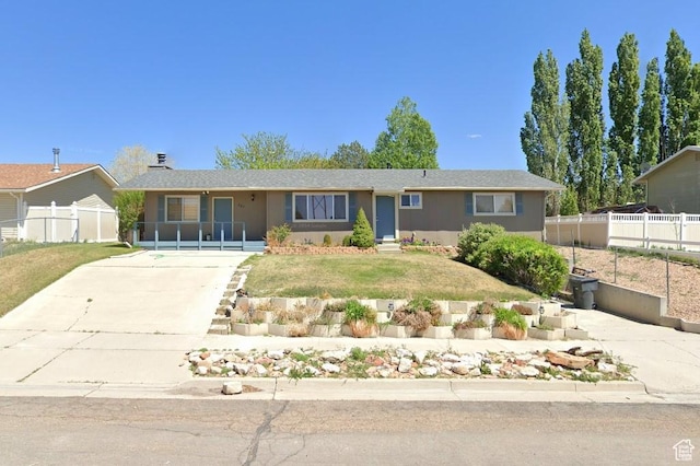 ranch-style home featuring a front yard, driveway, and fence