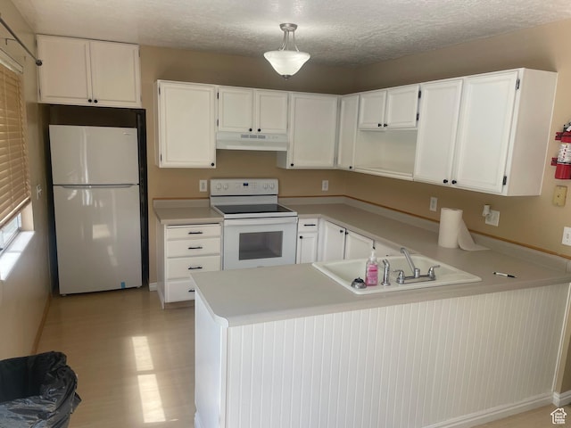 kitchen featuring white appliances, white cabinets, under cabinet range hood, and a peninsula