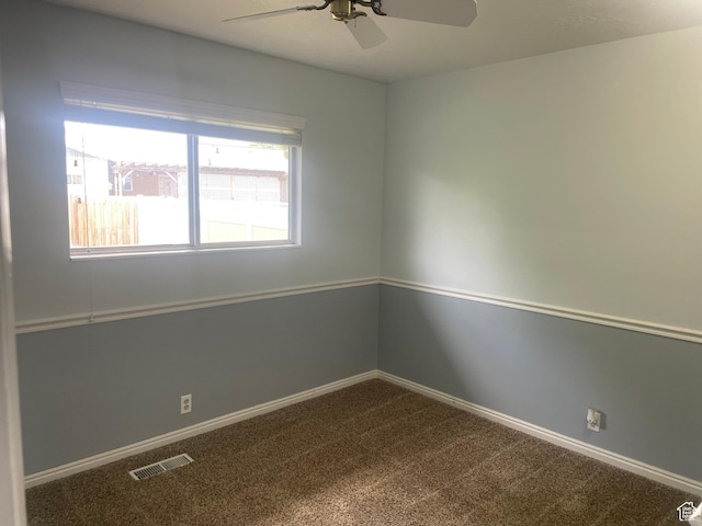 empty room featuring baseboards, visible vents, ceiling fan, and dark carpet