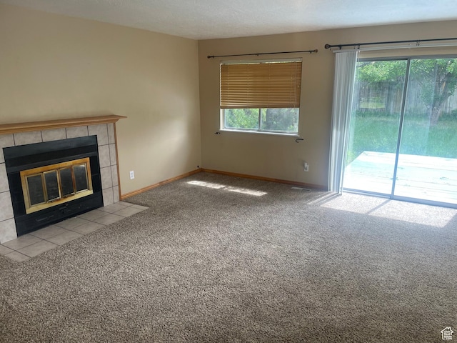 unfurnished living room featuring baseboards, a tile fireplace, carpet, and a textured ceiling