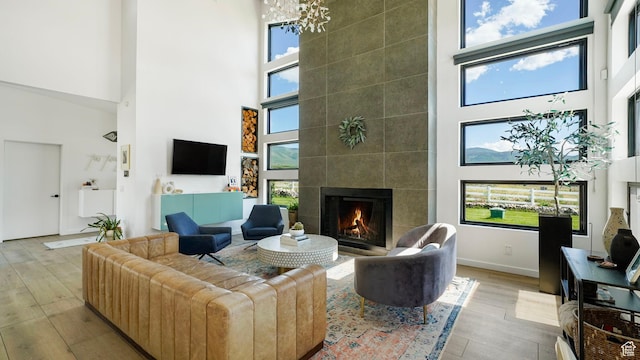 1245 E Draper Ln, Wallsburg, UT 84082 - living room featuring light wood-type flooring, a towering ceiling, a wealth of natural light, and a tiled fireplace