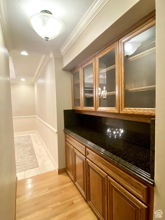 1387 E 260 N, Logan, UT 84321 - bar with decorative backsplash, crown molding, light hardwood / wood-style flooring, dark stone countertops, and a chandelier