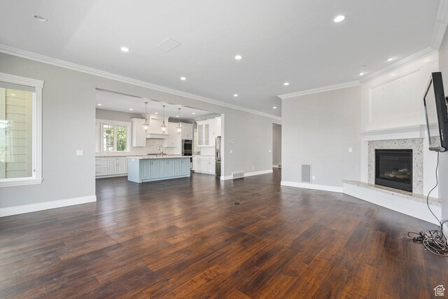 3128 E Hunters Ridge Way, Heber City, UT 84032 - unfurnished living room featuring a sink, dark wood-style floors, a glass covered fireplace, crown molding, and recessed lighting