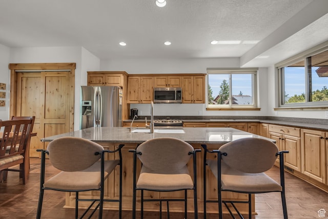 1126 Station Loop Rd, Park City, UT 84098 - kitchen featuring dark stone counters, hardwood / wood-style flooring, a kitchen island with sink, appliances with stainless steel finishes, and a breakfast bar