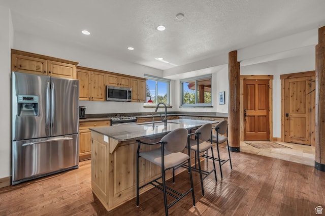 1126 Station Loop Rd, Park City, UT 84098 - kitchen with a kitchen breakfast bar, light wood-type flooring, dark stone countertops, a kitchen island with sink, and appliances with stainless steel finishes