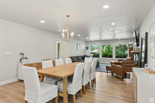 dining space with an inviting chandelier, a textured ceiling, and light hardwood / wood-style floors