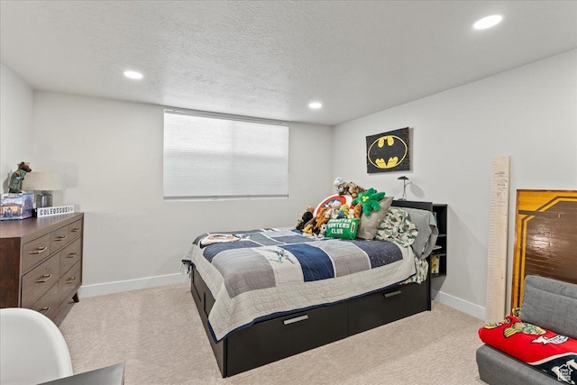 bedroom with light colored carpet and a textured ceiling