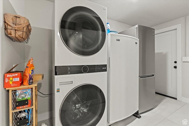 laundry room with light tile patterned floors and stacked washer / dryer