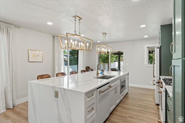 kitchen with sink, hanging light fixtures, white range with gas cooktop, stainless steel dishwasher, and a center island with sink