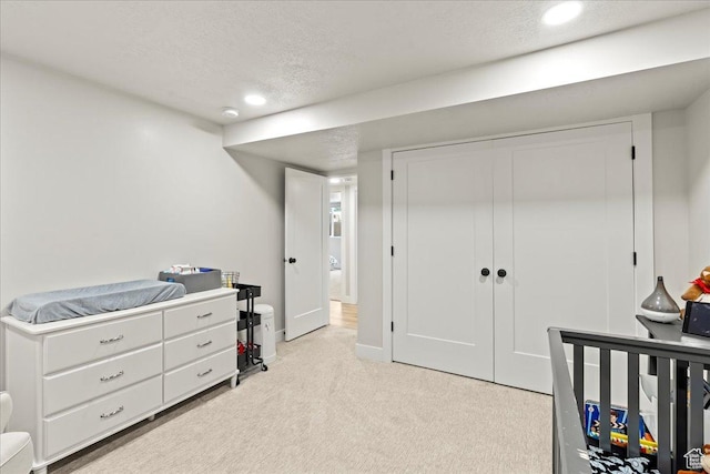 bedroom with light carpet, a closet, and a textured ceiling