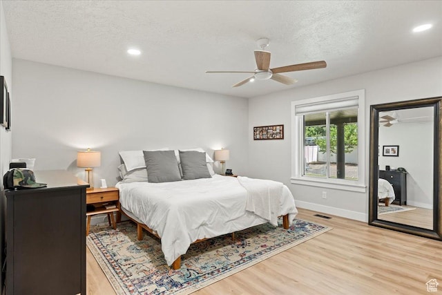 bedroom featuring ceiling fan, a textured ceiling, and light hardwood / wood-style floors