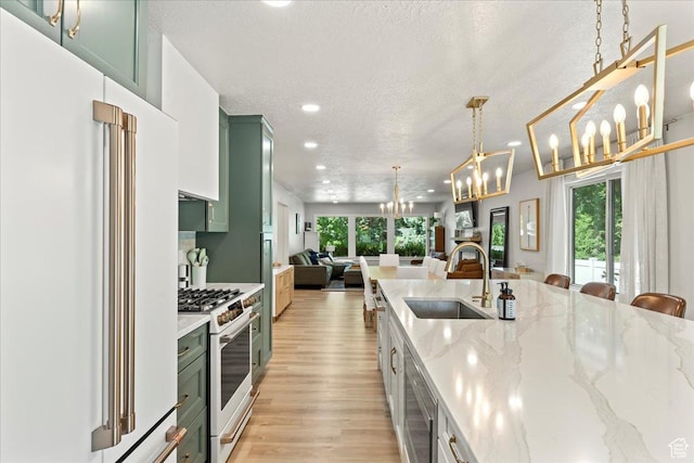 kitchen with sink, hanging light fixtures, green cabinets, high end fridge, and an inviting chandelier