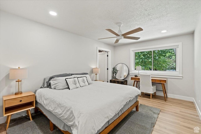 bedroom with ceiling fan, a textured ceiling, and light wood-type flooring