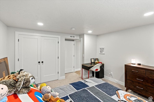 bedroom with light colored carpet, a closet, and a textured ceiling
