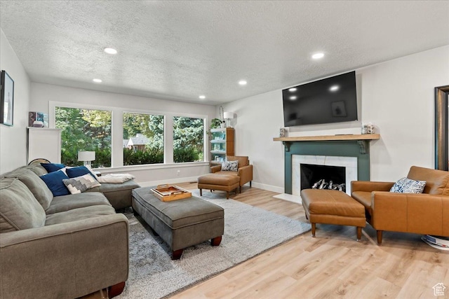 living room with a high end fireplace, wood-type flooring, and a textured ceiling