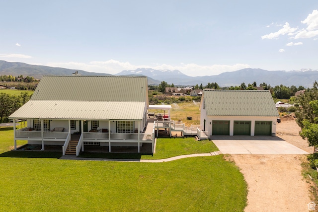 rear view of property with a lawn, a garage, a mountain view, and a porch