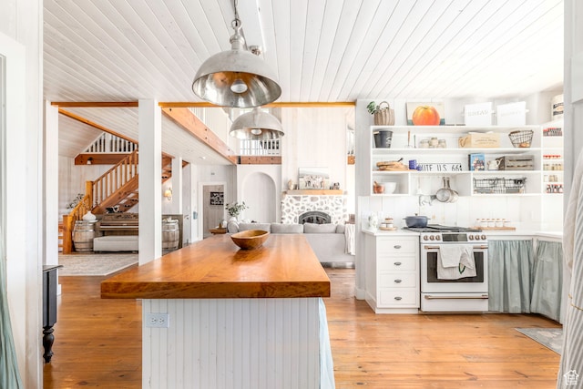 kitchen with high end stove, light hardwood / wood-style flooring, wood ceiling, and a tile fireplace