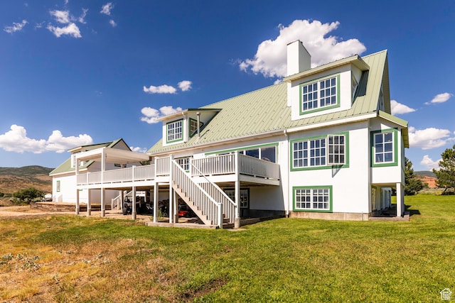 rear view of house featuring a wooden deck and a yard