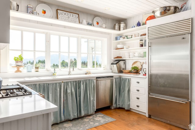 kitchen with light hardwood / wood-style flooring, white cabinetry, and appliances with stainless steel finishes