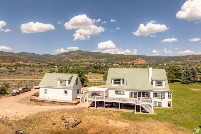 back of property featuring a yard and a deck with mountain view