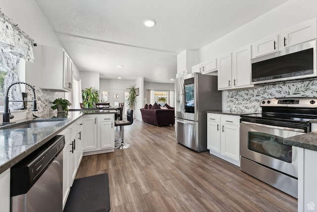 kitchen with white cabinets, backsplash, stainless steel appliances, and sink
