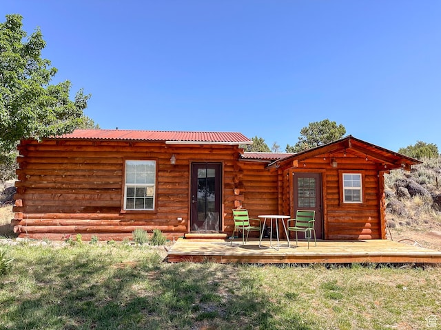 back of property featuring a wooden deck and a lawn