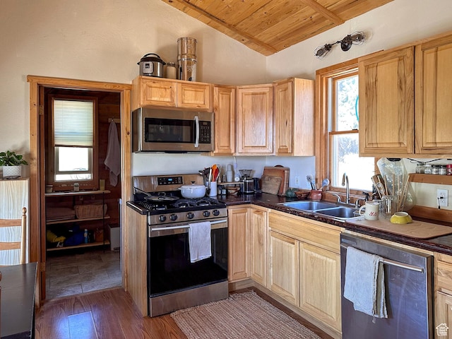 kitchen featuring vaulted ceiling, appliances with stainless steel finishes, light brown cabinetry, sink, and wood ceiling