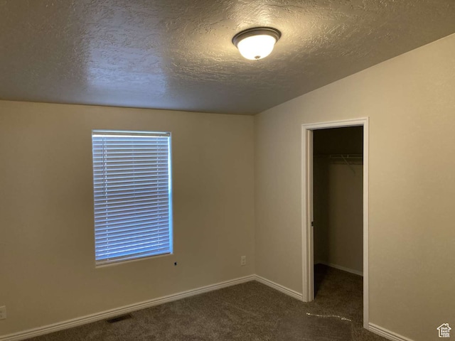 255 S 800 W, Escalante, UT 84726 - unfurnished bedroom featuring vaulted ceiling, a closet, a spacious closet, dark colored carpet, and a textured ceiling