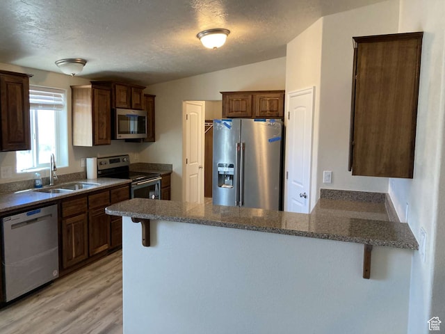 255 S 800 W, Escalante, UT 84726 - kitchen with light hardwood / wood-style flooring, kitchen peninsula, stainless steel appliances, a kitchen bar, and sink