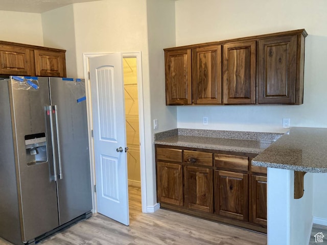 255 S 800 W, Escalante, UT 84726 - kitchen featuring dark stone countertops, a kitchen bar, stainless steel fridge, and light hardwood / wood-style flooring