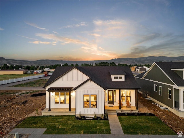 back house at dusk with a mountain view, a yard, and a porch