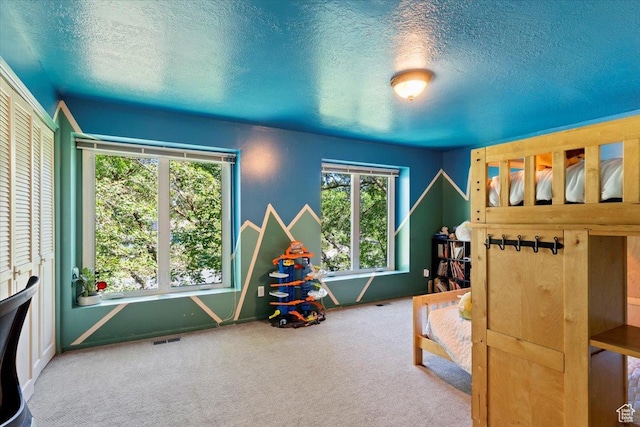 bedroom featuring carpet flooring, a textured ceiling, and multiple windows
