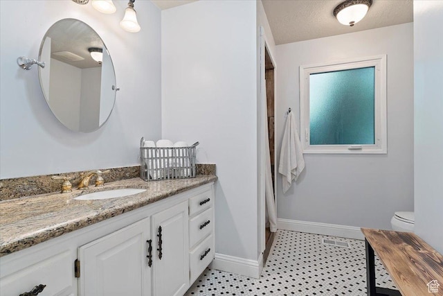 bathroom featuring vanity, a textured ceiling, and toilet
