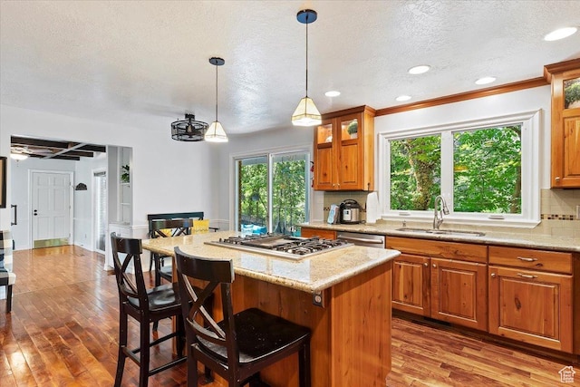 kitchen featuring backsplash, sink, appliances with stainless steel finishes, a kitchen island, and a breakfast bar area