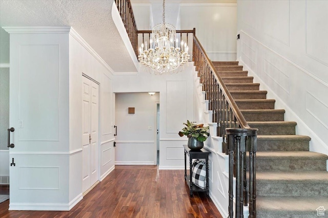 entrance foyer with a textured ceiling, dark hardwood / wood-style floors, an inviting chandelier, and ornamental molding
