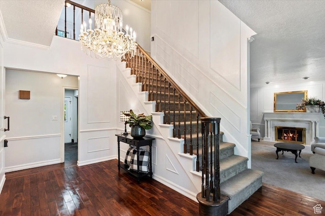 stairs featuring a textured ceiling, hardwood / wood-style flooring, an inviting chandelier, and ornamental molding