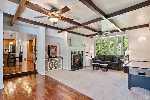 living room featuring ceiling fan, carpet floors, a fireplace, and coffered ceiling