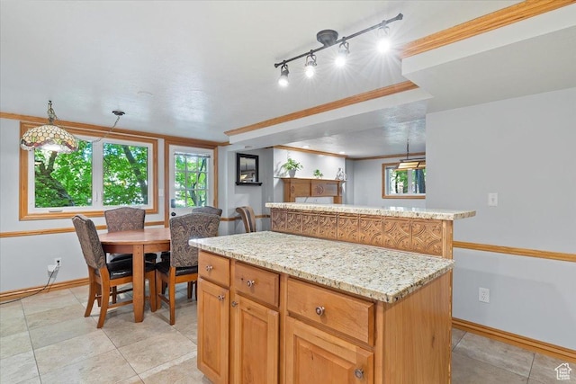 kitchen featuring decorative light fixtures, a center island, light stone countertops, and ornamental molding